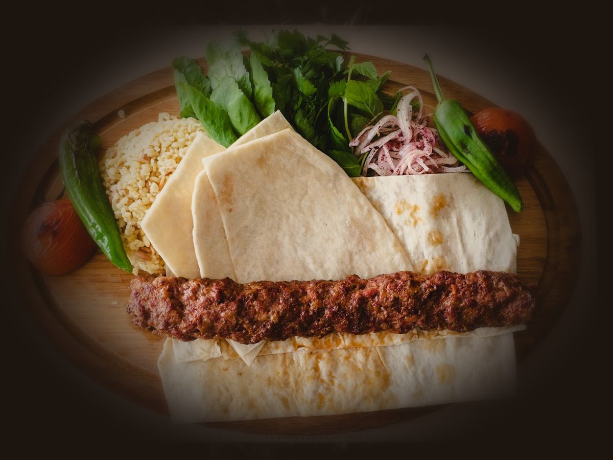 Adana servis — zırhla çekilmiş acılı kıyma kebabı, lavaş yatağında